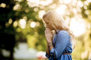 Woman praying outdoors as a symbol of Christ-centered forgiveness and spiritual healing