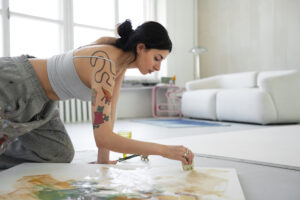 Woman painting on the floor in a bright studio, illustrating creative practice and letting go of perfectionism for Christian women in Frisco Texas
