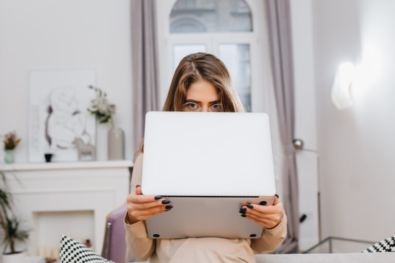 Woman holding a laptop in front of her face, symbolizing the limitations and misconceptions of using AI for therapy instead of human counseling.