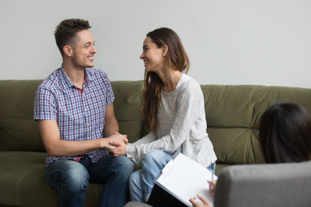 Couple smiling and holding hands during couples counseling session in Frisco TX