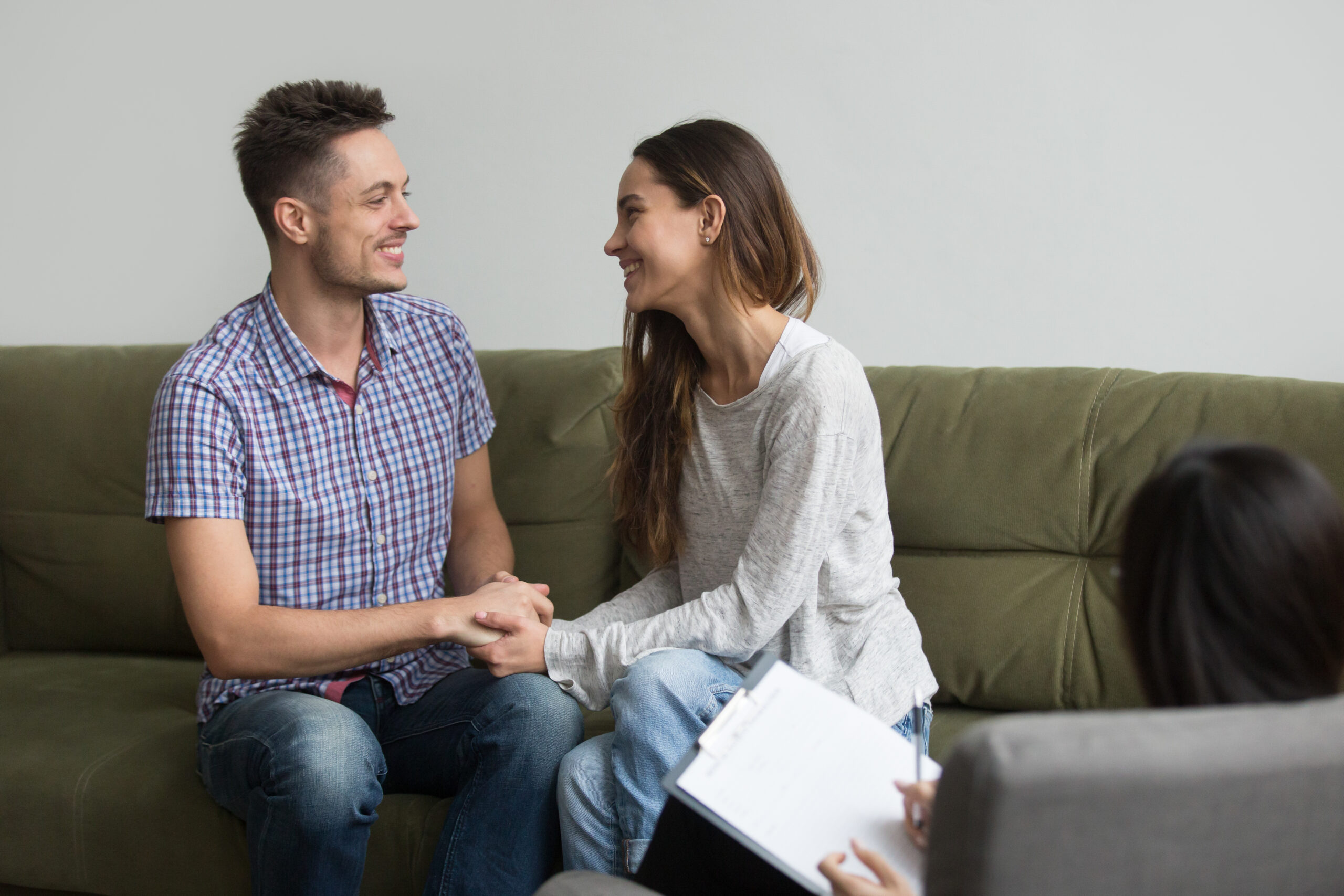 Couple smiling and holding hands during couples counseling session in Frisco TX