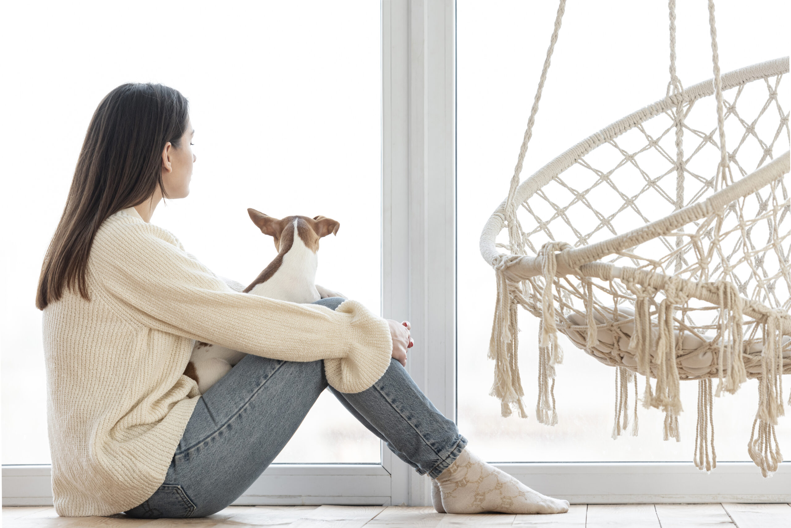 Woman sitting quietly by a window, reflecting, representing the grief of growing up with an absent or unavailable parent.